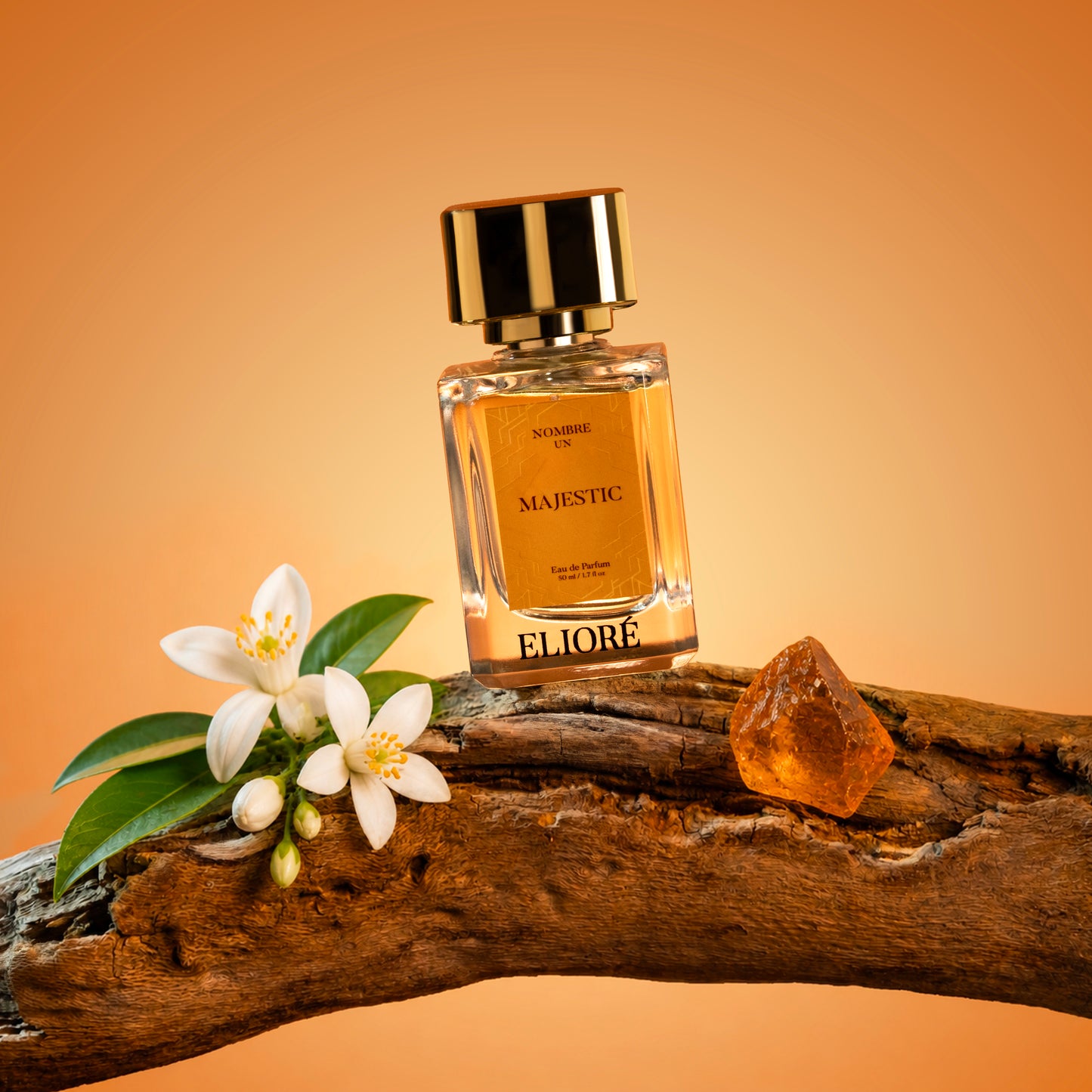 Perfume bottle labeled 'Majestic' by Eliore on a wooden surface with flowers and amber stone.