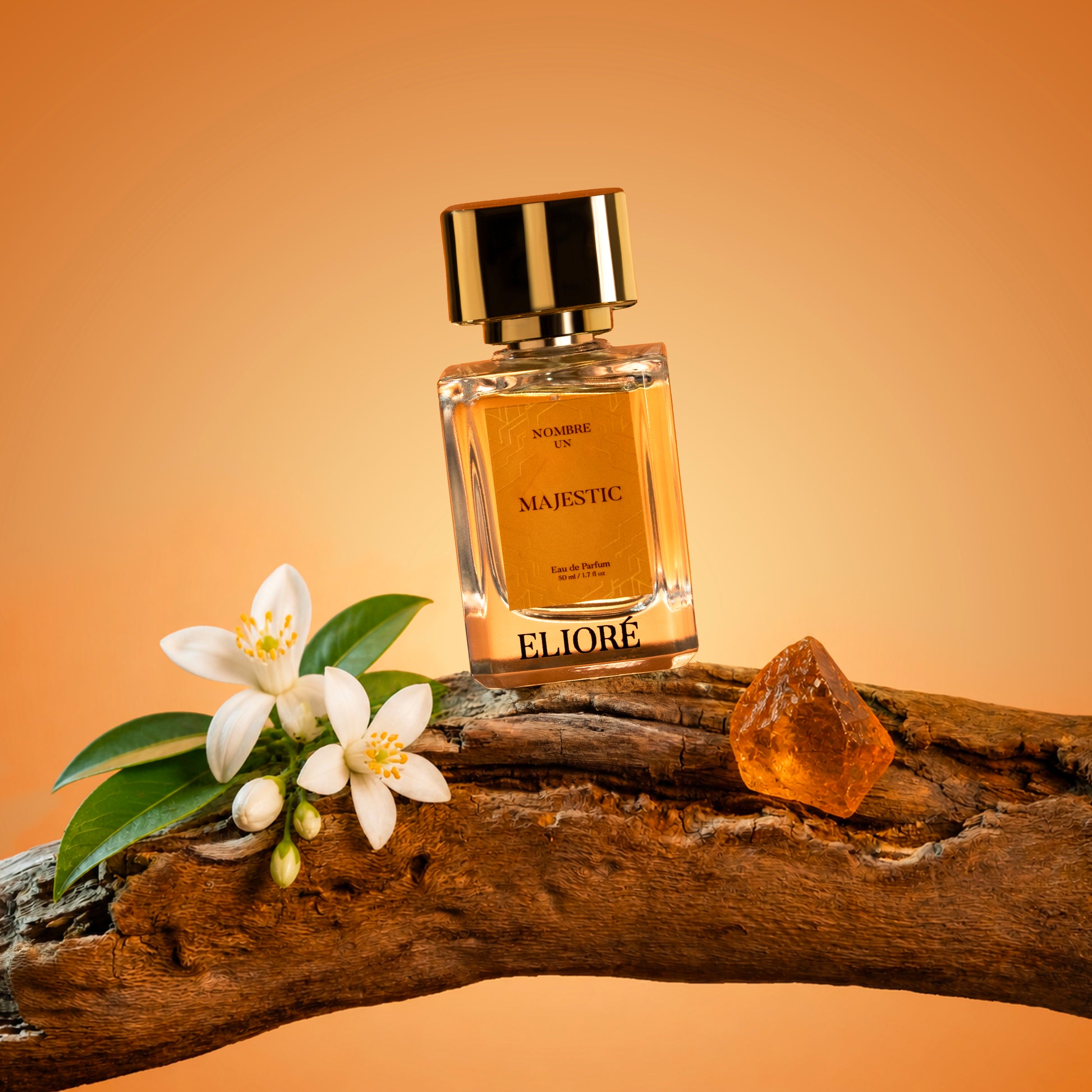 Perfume bottle labeled 'Majestic' by Eliore on a wooden surface with flowers and amber stone.
