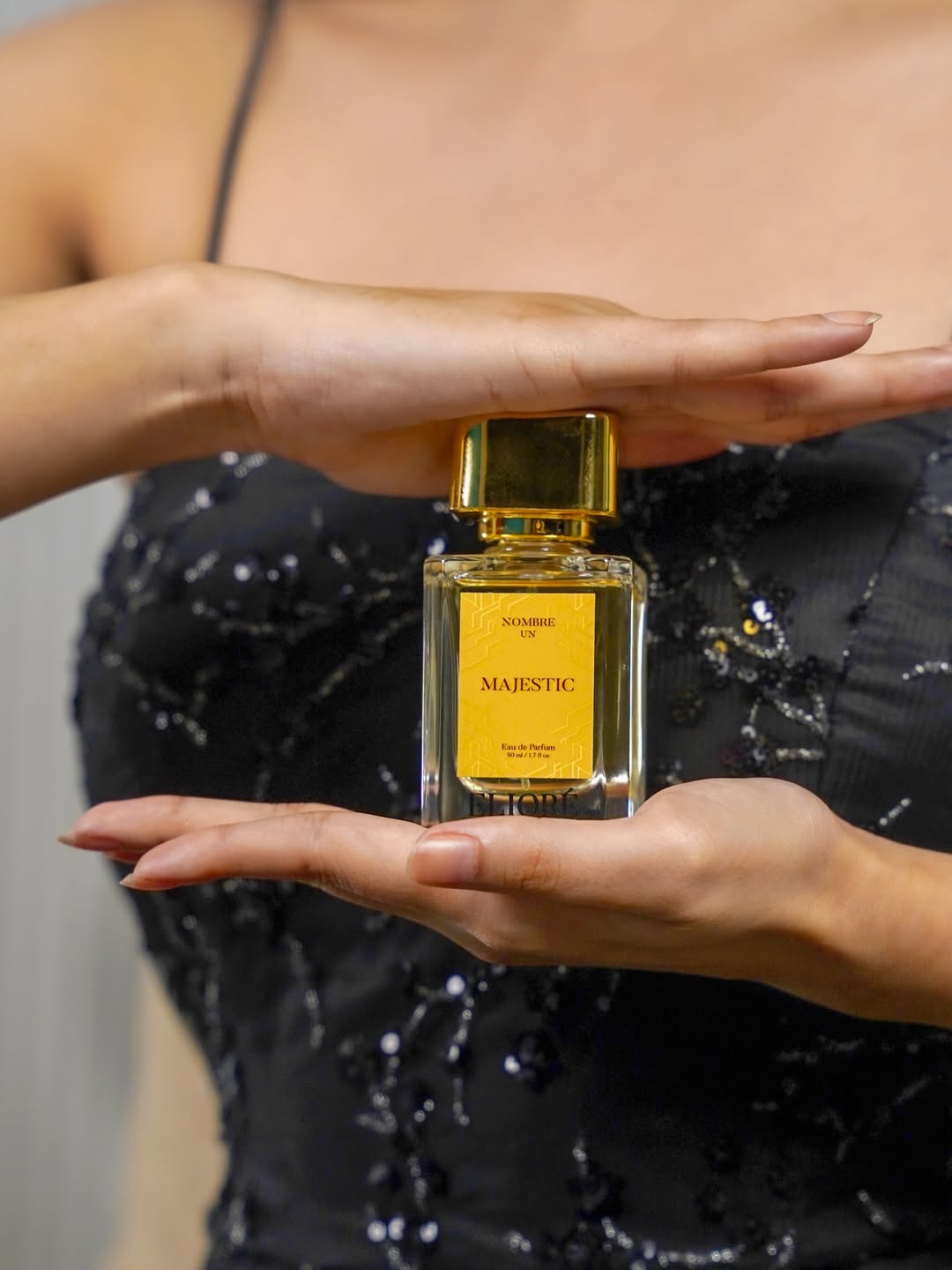 Person holding a 'Majestic' perfume bottle between their hands