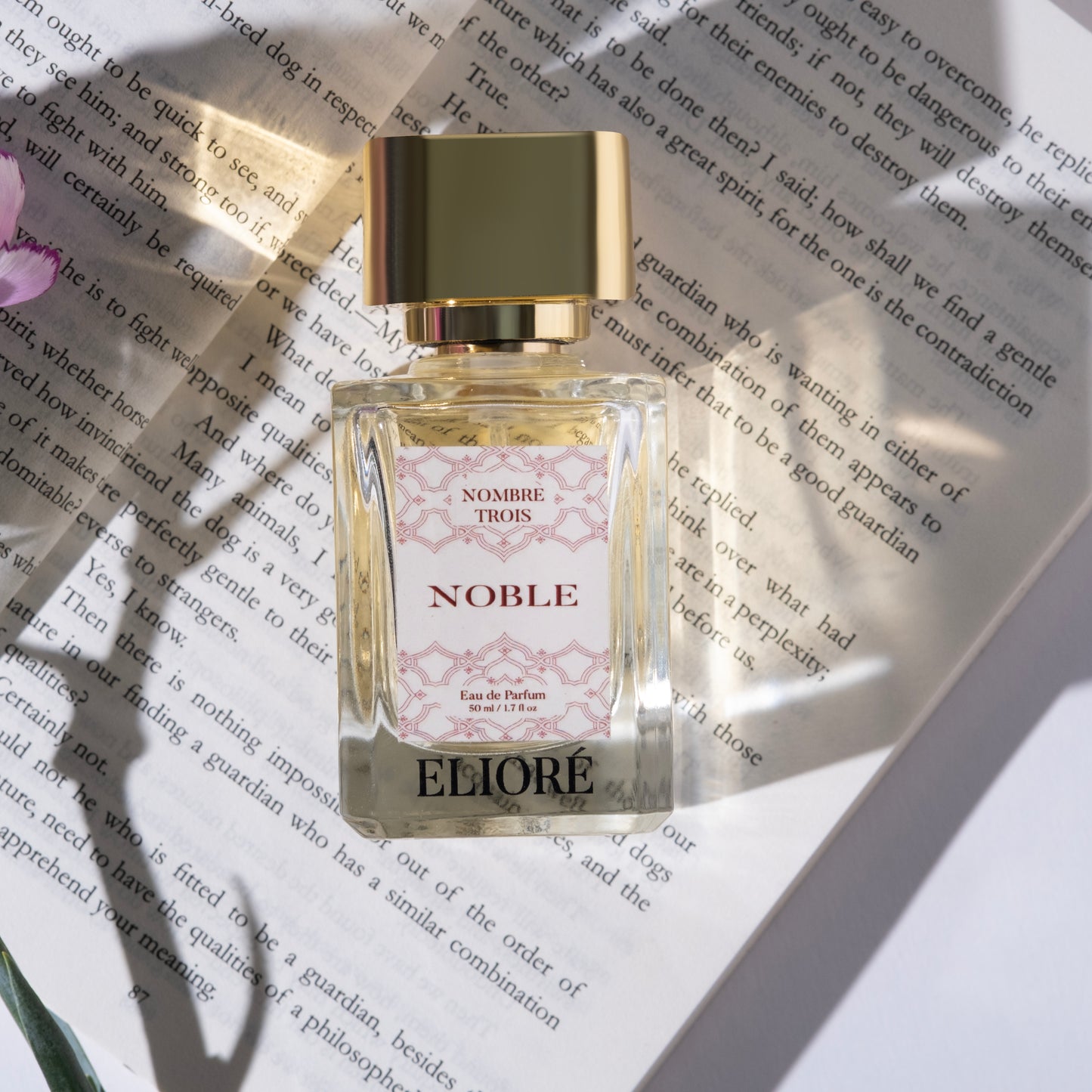Eliore perfume bottle on a book with a gold cap