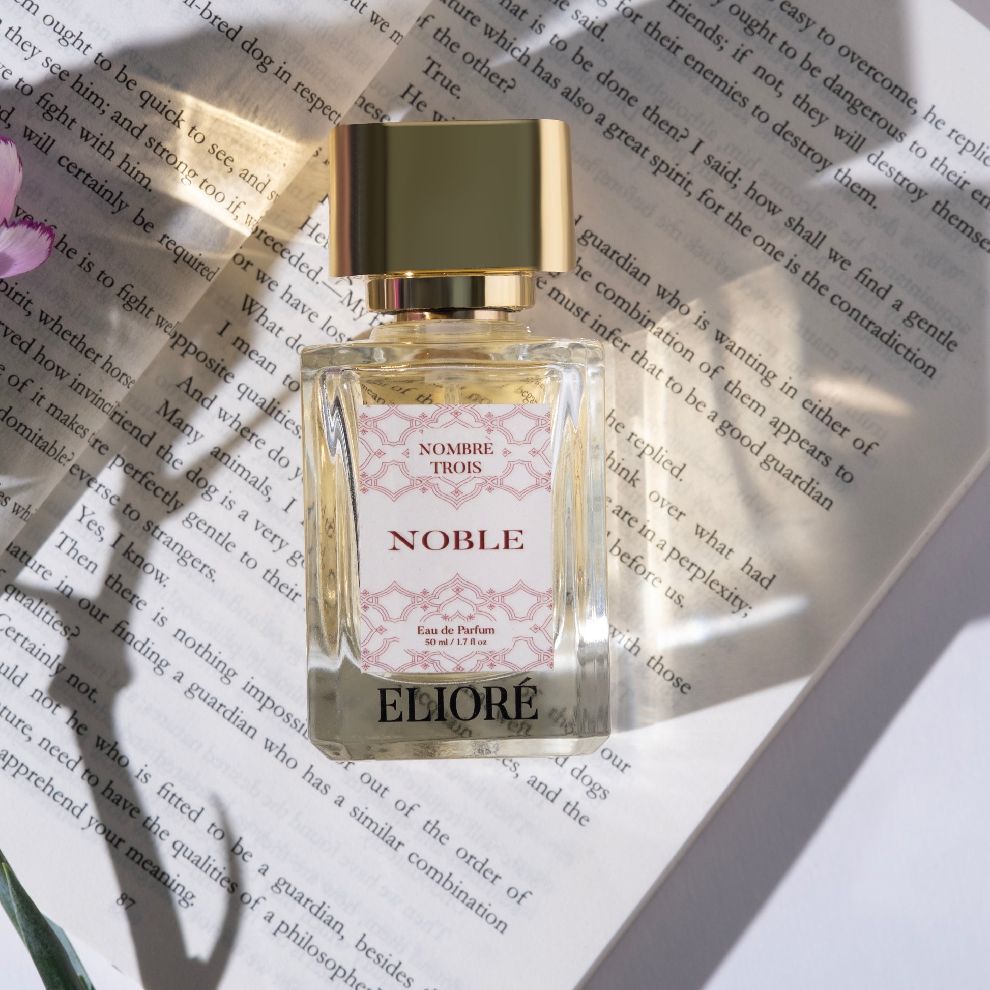 Eliore perfume bottle on a book with a gold cap