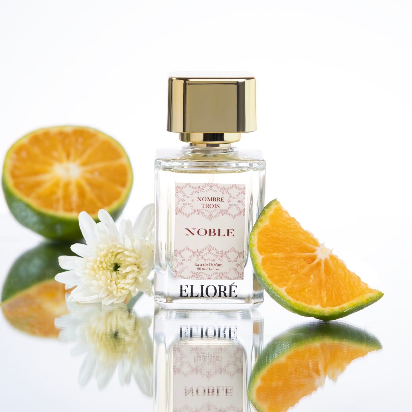 Perfume bottle labeled 'Eliore' with oranges and a flower on a reflective surface