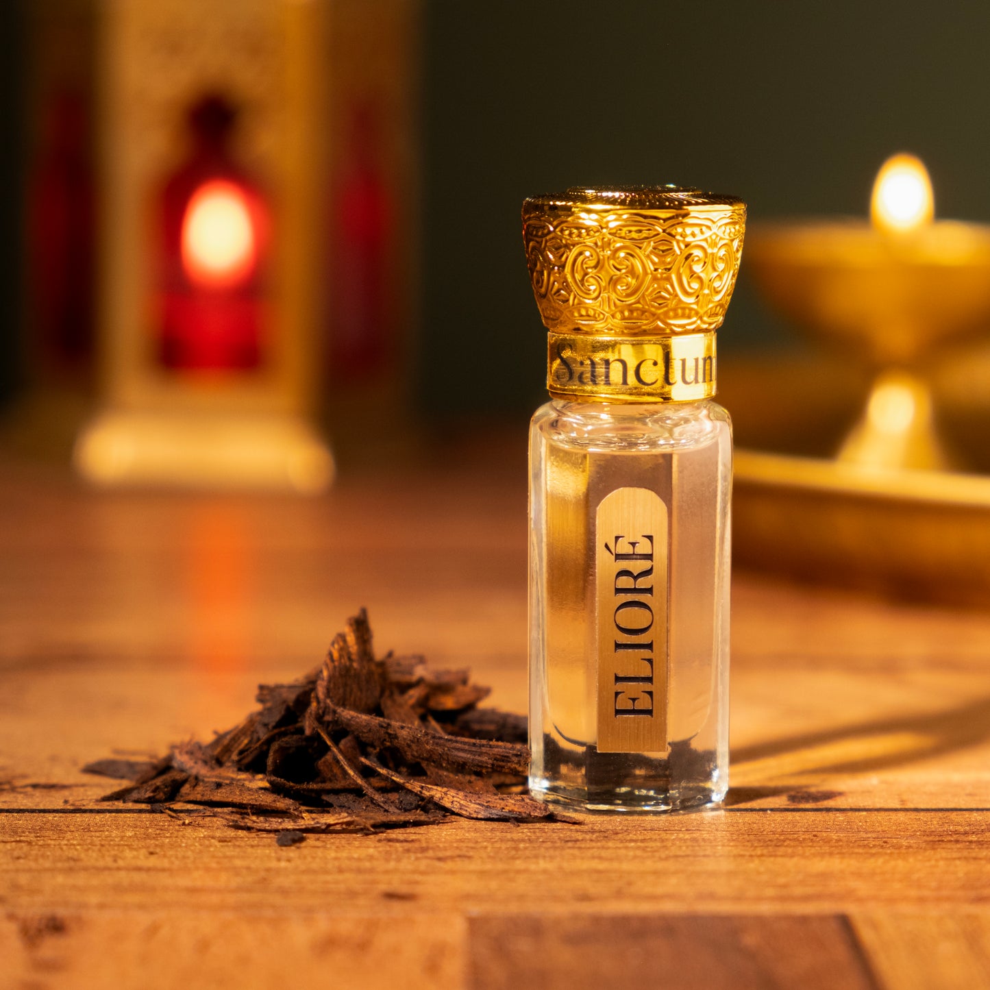 Perfume bottle labeled 'Eliore' with gold cap on a wooden surface, candles in the background