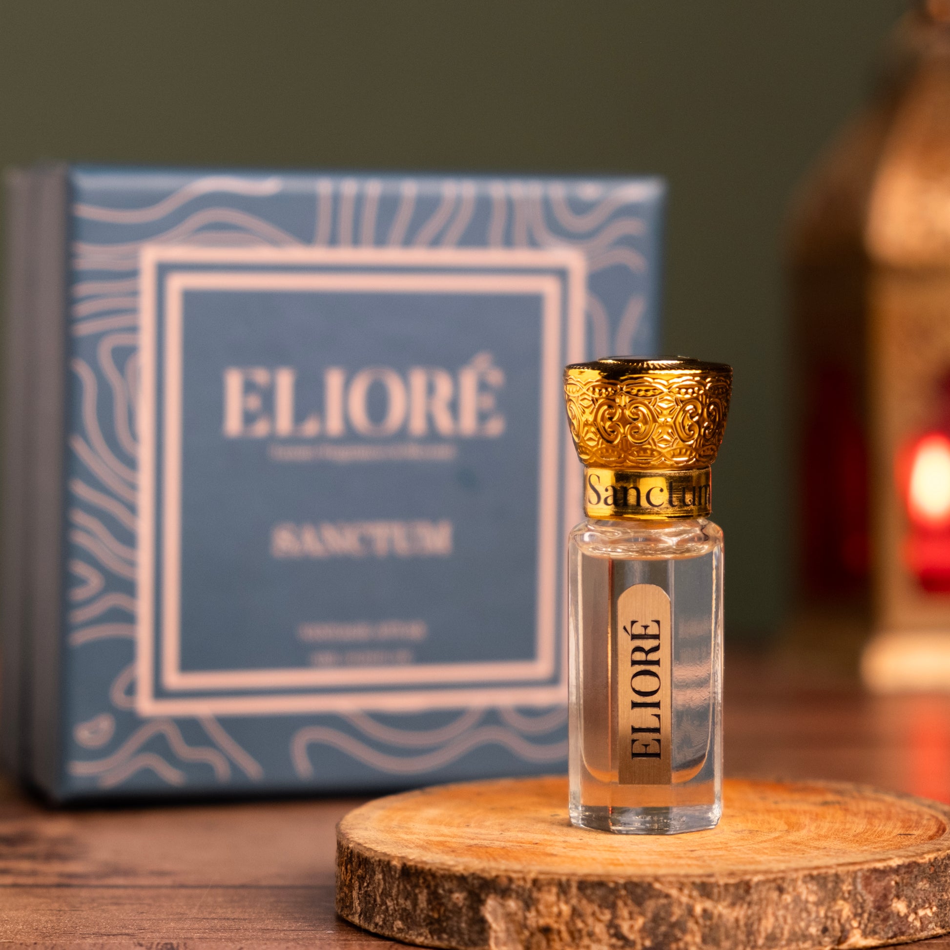 Eliore perfume bottle with gold cap on a wooden stand, box in the background