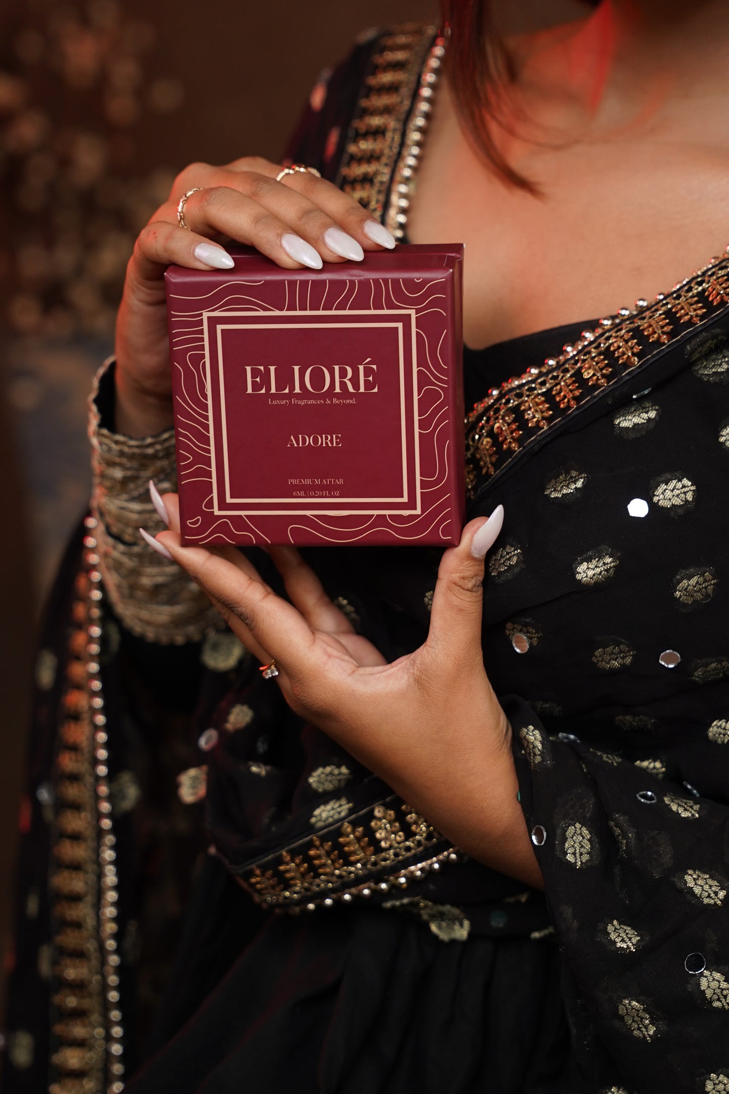 Person holding a maroon box with 'Eliore' branding against a blurred background