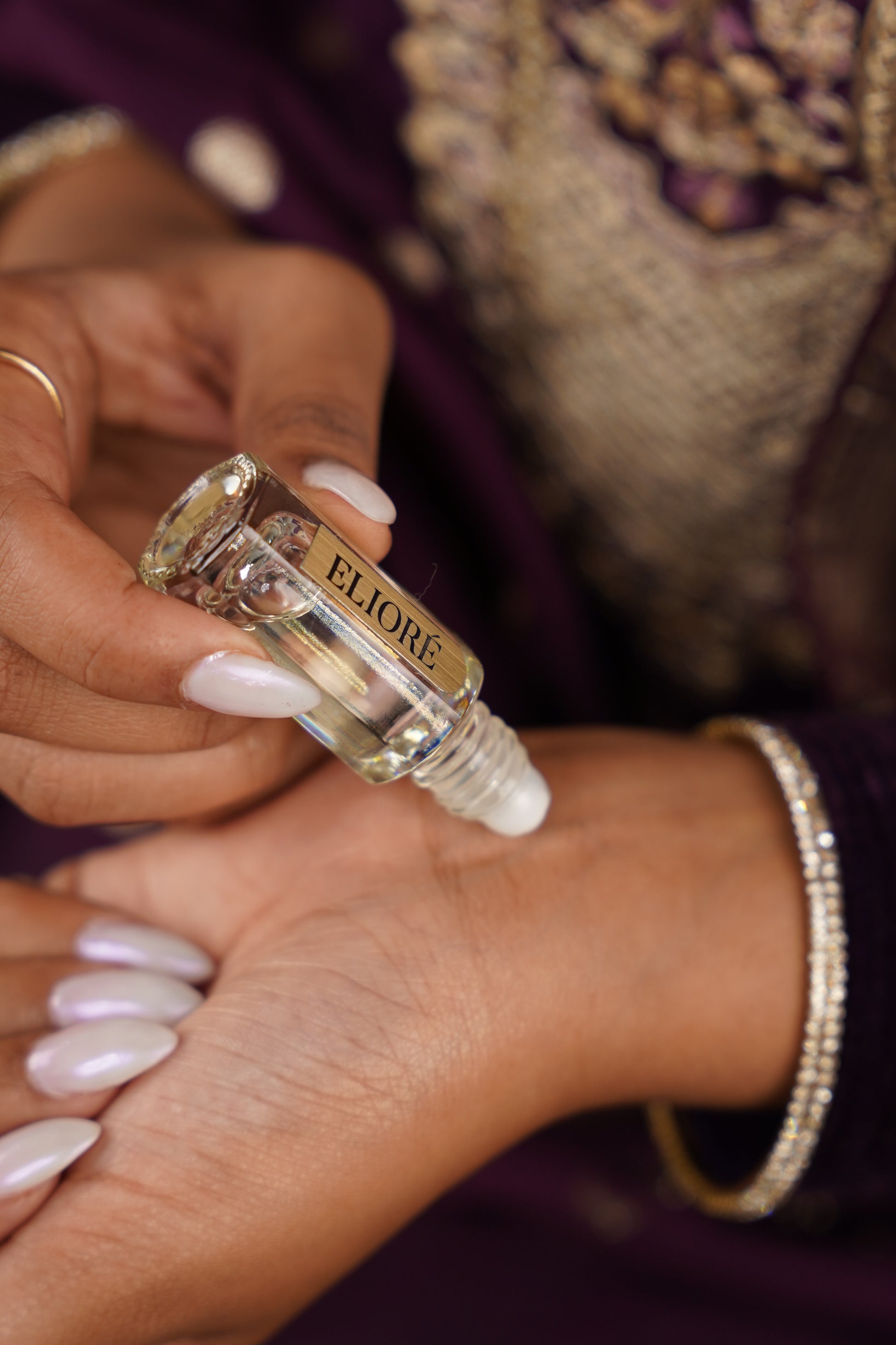 Close-up of a hand applying rollerball cherish attar to another hand.