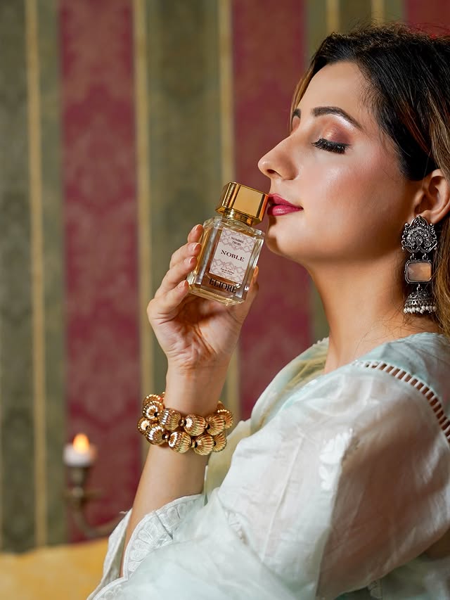 Woman holding a perfume bottle with a decorative background