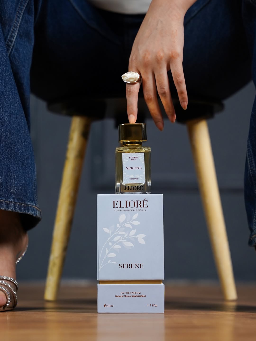 Eliore Serene perfume bottle and packaging on a wooden surface with a blurred background